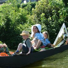 Barque traditionnelle des hortillonnages d'Amiens avec une mère et ses enfants en costume traditionnel à l'occasion du marché sur l'eau.